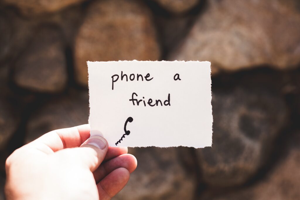 Image of a piece of paper in a person's hand with the words phone a friend.