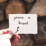 Image of a piece of paper in a person's hand with the words phone a friend.