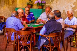 A group of older men, all close friends sitting around a table playing cards.