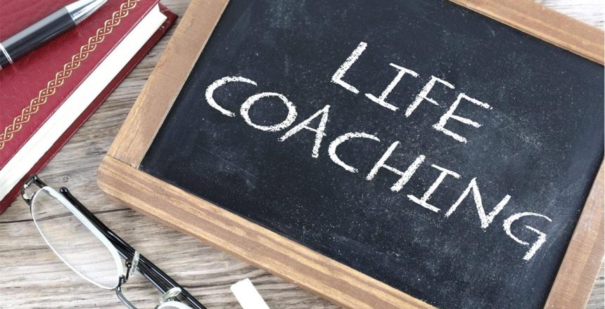 Chalk board on a table with the words Life Coaching written on it.